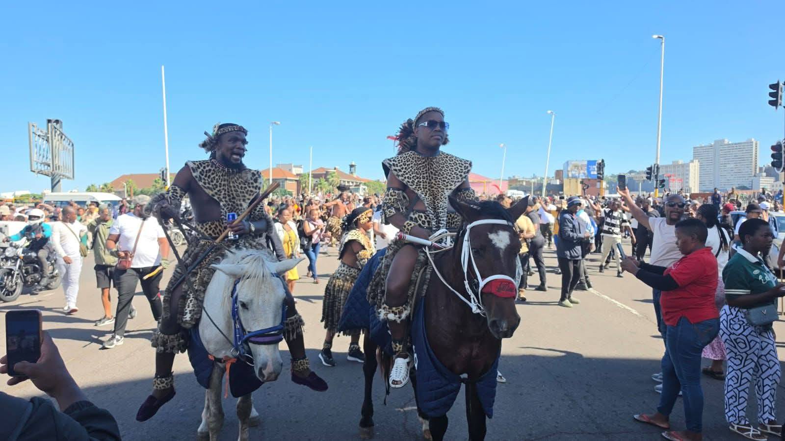 Ngizwe Mchunu ridding a brown horse with Hlobelihle Ntombela on the the white horse leading an anti immigration March in Durban.