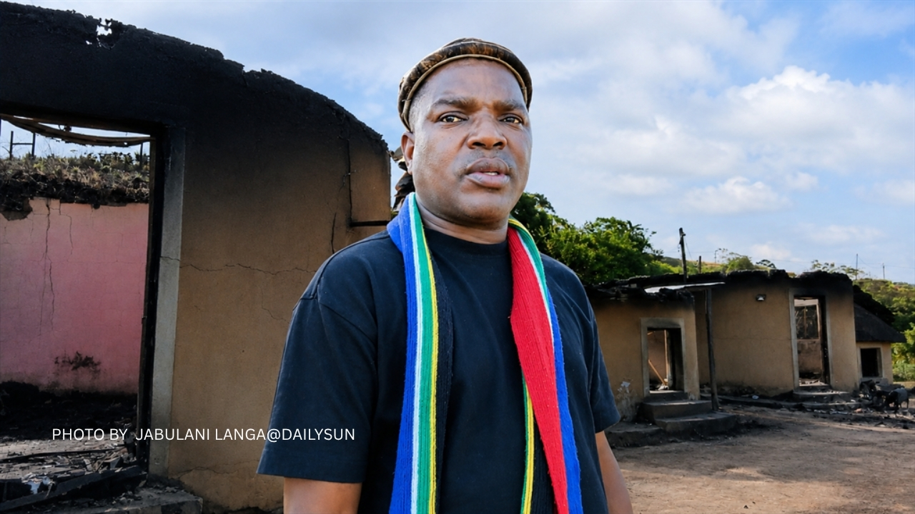 Ngizwe Mchunu at his home. Behind him are his round houses after being burned down.